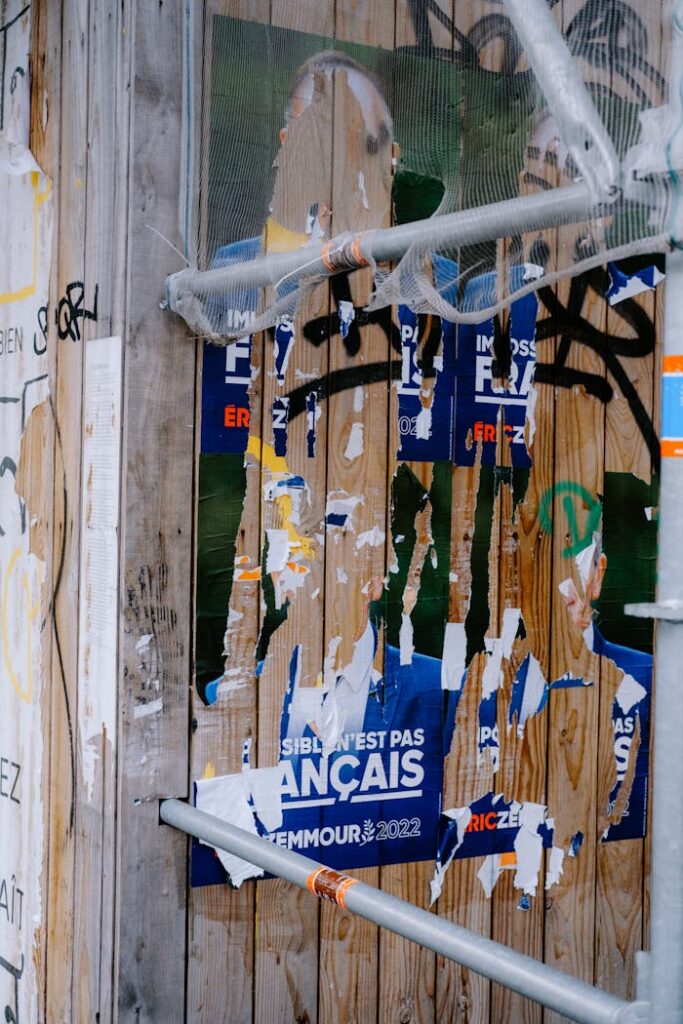 Shredded French election posters cover a graffiti-filled city wall.
